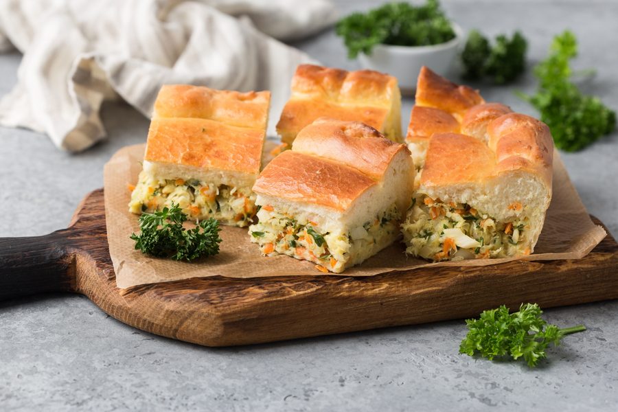 Куски пирога с треской и овощами на доске