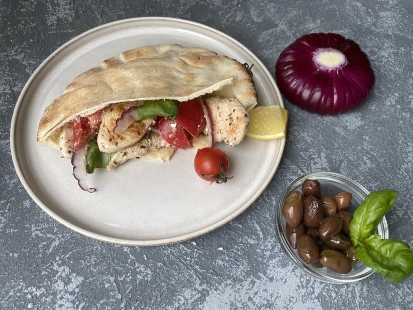Пита с греческим салатом и курицей, рядом оливки и красный лук