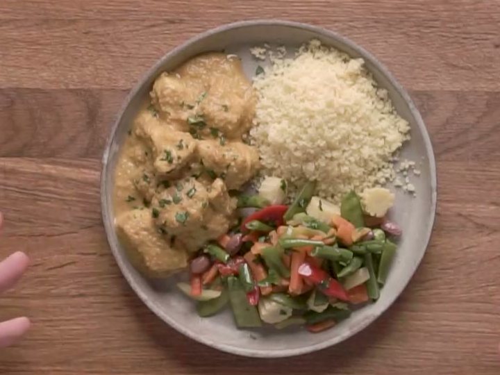 Индейка в арахисовом соусе, кус-кус и обжаренные овощи на тарелке