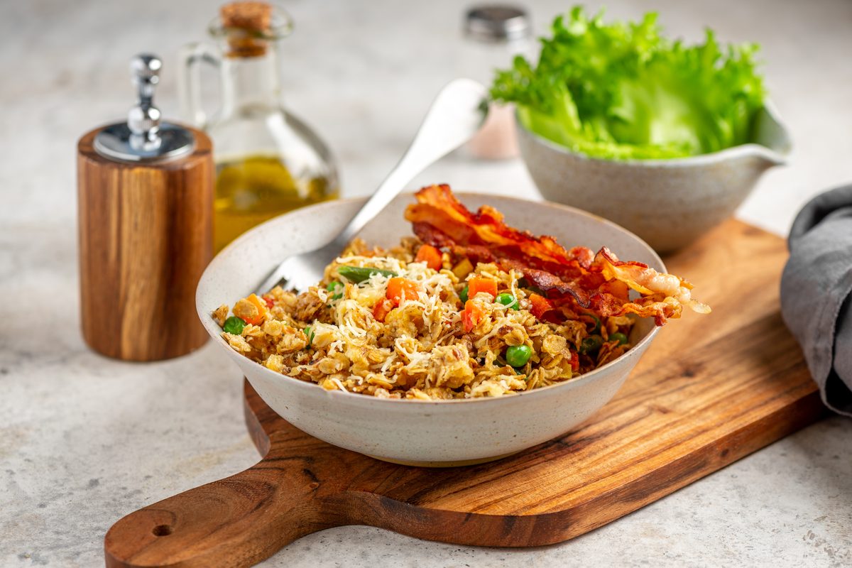 Жареная овсянка с овощами и беконом в миске